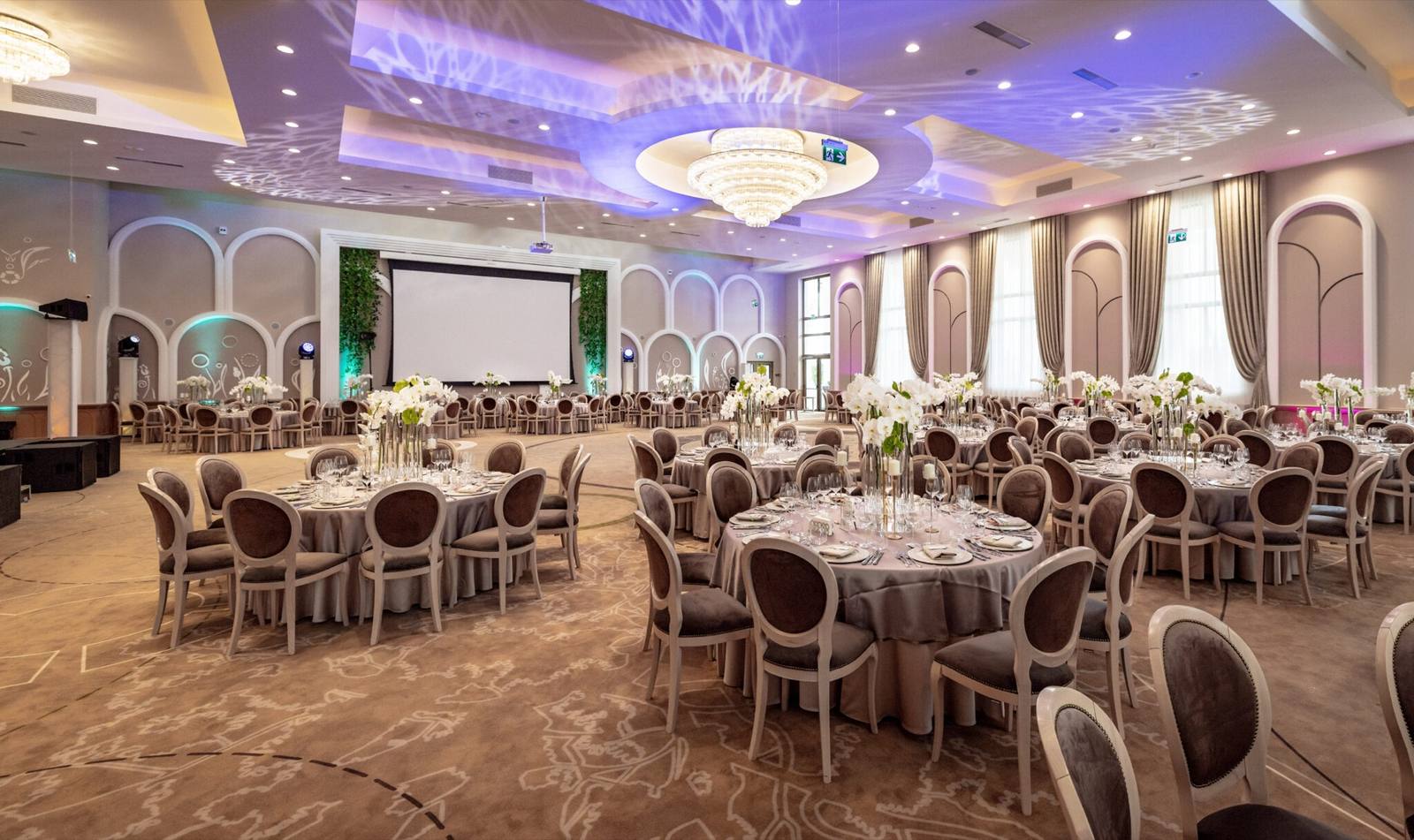 Hall set for a wedding, with architectural lighting and floral arrangements